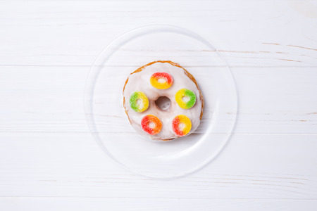 donut in sugar glaze with candied fruit on a transparent plateの写真素材
