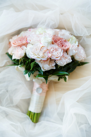 Golden wedding rings lie in a bud of pink rose. Wedding rings lie on a flower budの写真素材