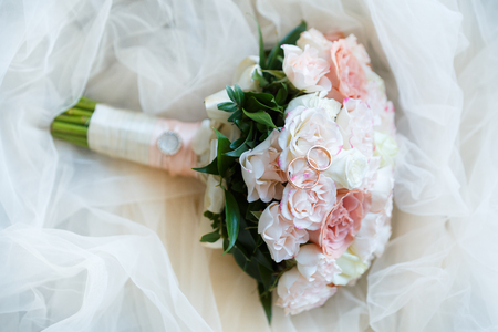 Golden wedding rings lie in a bud of pink rose. Wedding rings lie on a flower budの写真素材