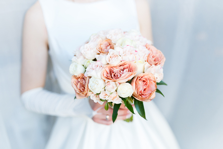 Bride holding wedding bouquet of roses and beautiful flowersの写真素材