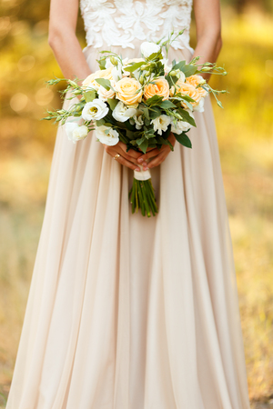 Charming and delicate bride holding bouquet with roses. Yellow and white roses in hand of the brideの写真素材