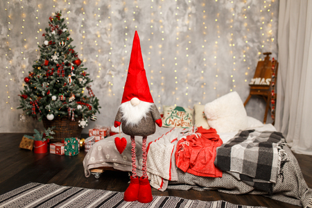 Cute winter gnome is waiting for christmas near the Christmas tree at home. Christmas time is near.の写真素材