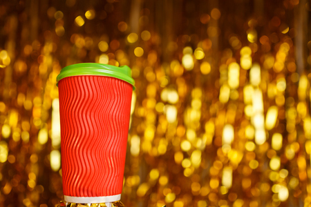 Christmas red cardboard cup of coffee on background with golden metafanの写真素材