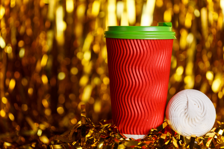 Christmas red cardboard cup of coffee with marshmallow on background with golden metafanの写真素材