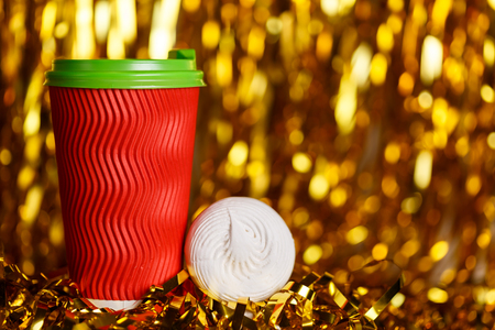 Christmas red cardboard cup of coffee with marshmallow on background with golden metafanの写真素材