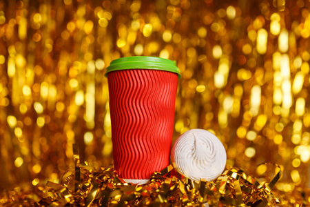 Christmas red cardboard cup of coffee with marshmallow on background with golden metafanの写真素材