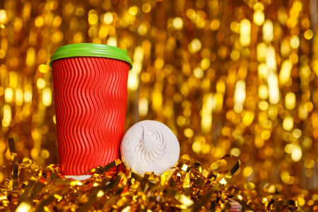 Christmas red cardboard cup of coffee with marshmallow on background with golden metafanの写真素材