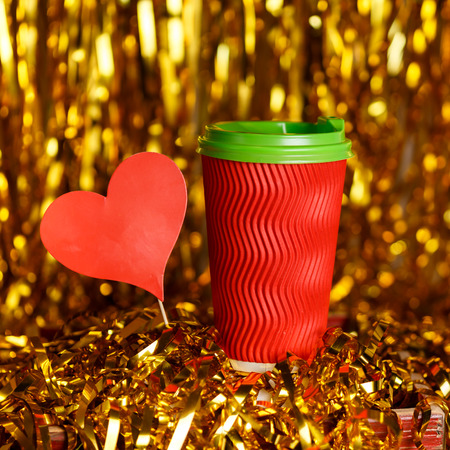 Christmas red cardboard cup of coffee with marshmallow on background with golden metafanの写真素材