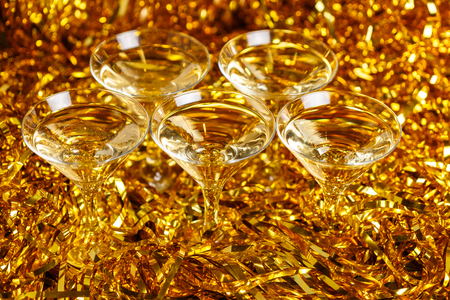 Glasses of champagne with golden confetti, glitter, serpentine and lights. Night of celebration conceptの写真素材