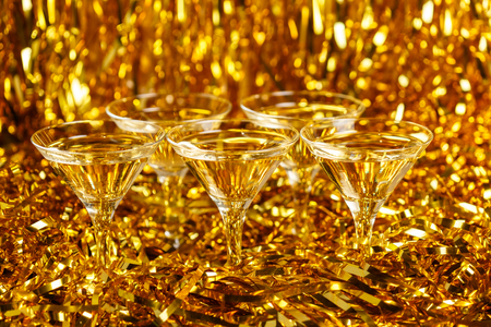 Glasses of champagne with golden confetti, glitter, serpentine and lights. Night of celebration conceptの写真素材