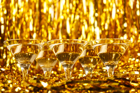 Glasses of champagne with golden confetti, glitter, serpentine and lights. Night of celebration conceptの写真素材