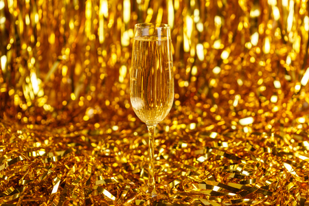 Glass of champagne with golden confetti, glitter and serpentine. Night of celebration conceptの写真素材