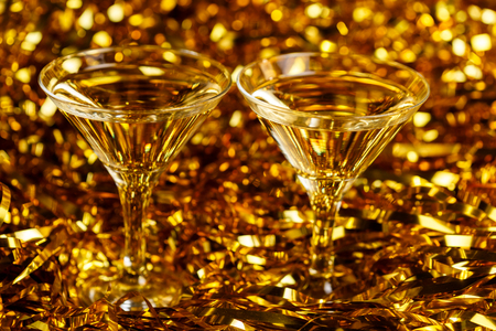Two glasses of champagne with golden confetti, glitter, serpentine and lights. Night of celebration conceptの写真素材