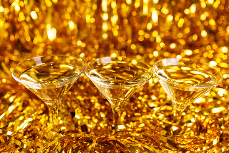 Glasses of champagne with golden confetti, glitter, serpentine and lights. Night of celebration conceptの写真素材