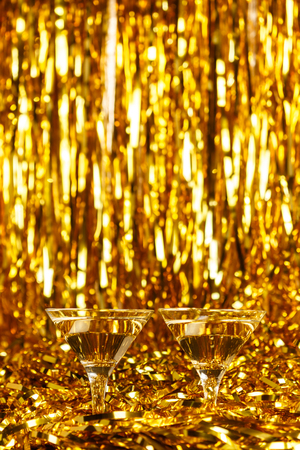 Two glasses of champagne with golden confetti, glitter, serpentine and lights. Night of celebration conceptの写真素材