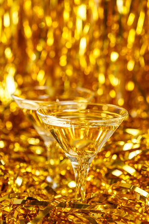 Two glasses of champagne with golden confetti, glitter, serpentine and lights. Night of celebration conceptの写真素材