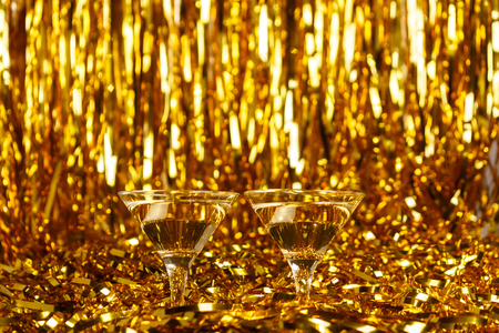 Two glasses of champagne with golden confetti, glitter, serpentine and lights. Night of celebration conceptの写真素材
