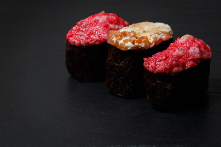 Gunkan Maki Sushi with with salmon on a black stone slate. Sushi menu. Japanese food. Trend color 2019 coral. Background image.の写真素材