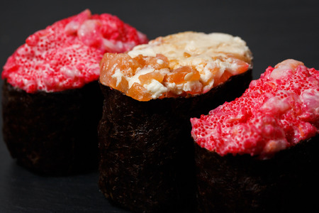 Gunkan Maki Sushi with with salmon on a black stone slate. Sushi menu. Japanese food. Trend color 2019 coral. Background image.の写真素材
