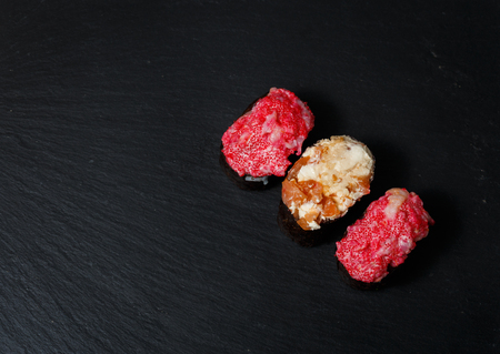 Gunkan Maki Sushi with with salmon on a black stone slate. Sushi menu. Japanese food. Trend color 2019 coral. Background image.の写真素材