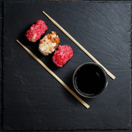 Gunkan Maki Sushi with salmon on a black stone slate. Japanese food with bamboo sticks and soy sauce. Trend color 2019 coral. Sushi menu. Background image.の写真素材