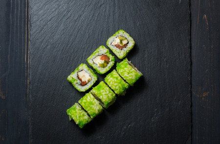 Japanese sushi rolls served on stone slate on dark background. Sushi background. Asian or Japanese food.の写真素材