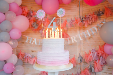 Delicious birthday cream cake with candles on the background with balloons. Beautiful cake with pink decoration for girl. Girl's birthday.の写真素材