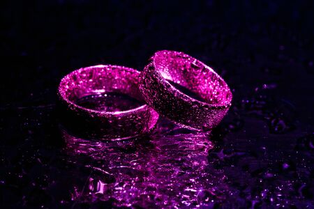 Beautiful wedding rings with violet neon lightsの写真素材