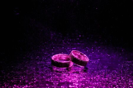 Beautiful wedding rings with violet neon lightsの写真素材