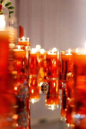 Wedding rings with precious stones on the mirror with many red candles. Beautiful wedding rings with reflection in the mirror.の写真素材