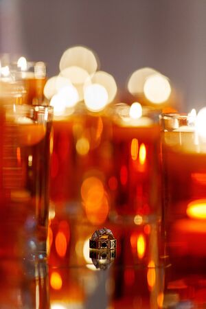 Wedding rings with precious stones on the mirror with many red candles. Beautiful wedding rings with reflection in the mirror.の写真素材