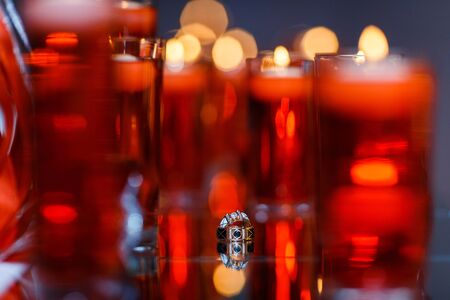 Wedding rings with precious stones on the mirror with many red candles. Beautiful wedding rings with reflection in the mirror.の写真素材
