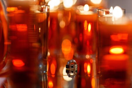 Wedding rings with precious stones on the mirror with many red candles. Beautiful wedding rings with reflection in the mirror.の写真素材