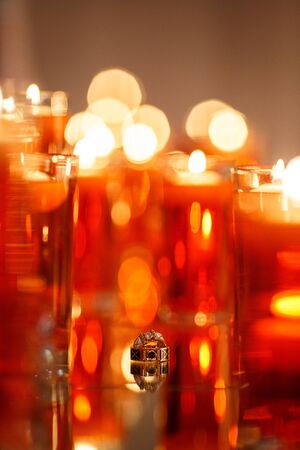 Wedding rings with precious stones on the mirror with many red candles. Beautiful wedding rings with reflection in the mirror.の写真素材