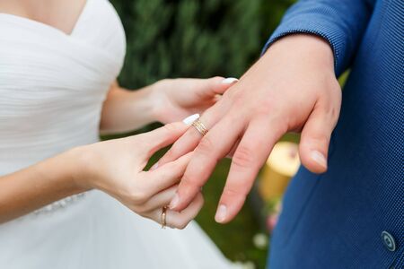 Hands of wedding couple putting golden rings to finger of each other during the ceremony. Newlyweds with rings on the ceremony.の写真素材