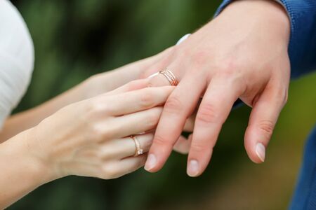 Hands of wedding couple putting golden rings to finger of each other during the ceremony. Newlyweds with rings on the ceremony.の写真素材