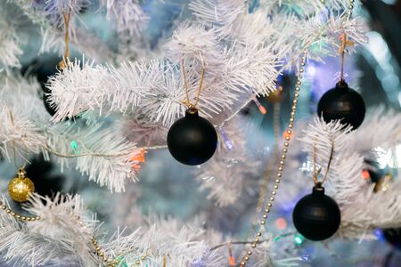 Christmas tree with black and golden christmas balls. De focused Lights on background.の写真素材