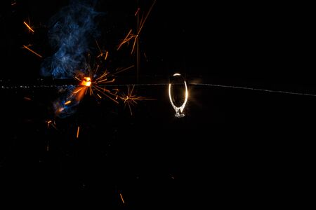 Wedding engagement ring on burning bengal light with many sparks and water spray on dark background. Marriage proposal for Christmas.の写真素材