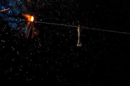 Wedding engagement ring on burning bengal light with many sparks and water spray on dark background. Marriage proposal for Christmas.の写真素材