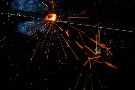 Wedding engagement ring on burning bengal light with many sparks and water spray on dark background. Marriage proposal for Christmas.の写真素材