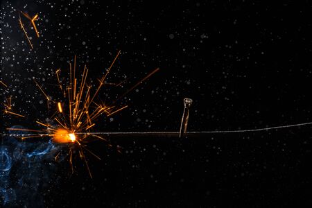 Wedding engagement ring on burning bengal light with smoke and many sparks on dark background. Marriage proposal for Christmas.の写真素材