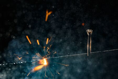 Wedding engagement ring on burning bengal light with smoke and many sparks on dark background. Marriage proposal for Christmas.の写真素材
