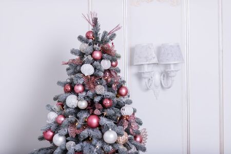 Beautiful New Year Tree decorated with colorful packed gifts and balls in studio against white background with empty place/space for Christmas text postcard concept.の写真素材