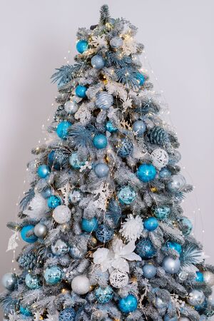 Beautiful New Year Tree decorated with colorful packed gifts and balls in studio against white background with empty place/space for Christmas text postcard concept.の写真素材