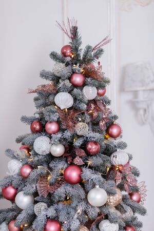 Beautiful New Year Tree decorated with colorful packed gifts and balls in studio against white background with empty place/space for Christmas text postcard concept.の写真素材
