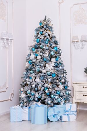 Christmas tree in the room decorated with toys and lay next to the gifts in boxesの写真素材