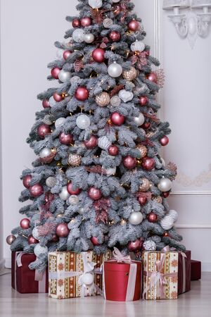 Christmas tree in the room decorated with toys and lay next to the gifts in boxesの写真素材