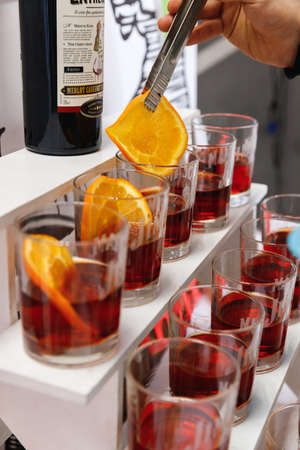 Barman is decorating a Negroni orange cocktail. Glass of delicious Negroni cocktail with slice of orange.のeditorial素材