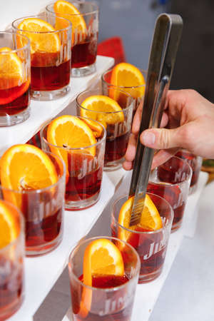 Barman is decorating a Negroni orange cocktail. Glass of delicious Negroni cocktail with slice of orange.のeditorial素材