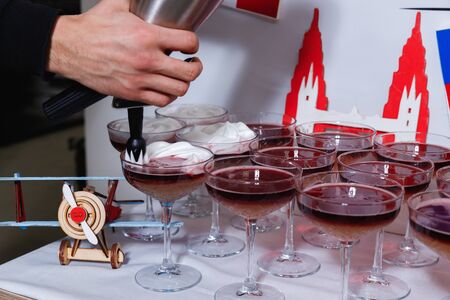 Bartender pouring a New York sour cocktail from the steel shaker to a glass on the bar counterの写真素材
